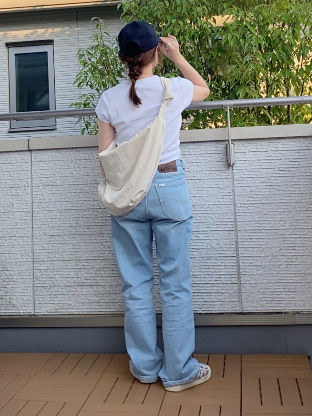 ホワイト系のTシャツ/カットソー、ブルー系のデニムパンツ、ホワイト系のショルダーバッグを着用したレディースの夏コーディネートの3枚目の写真