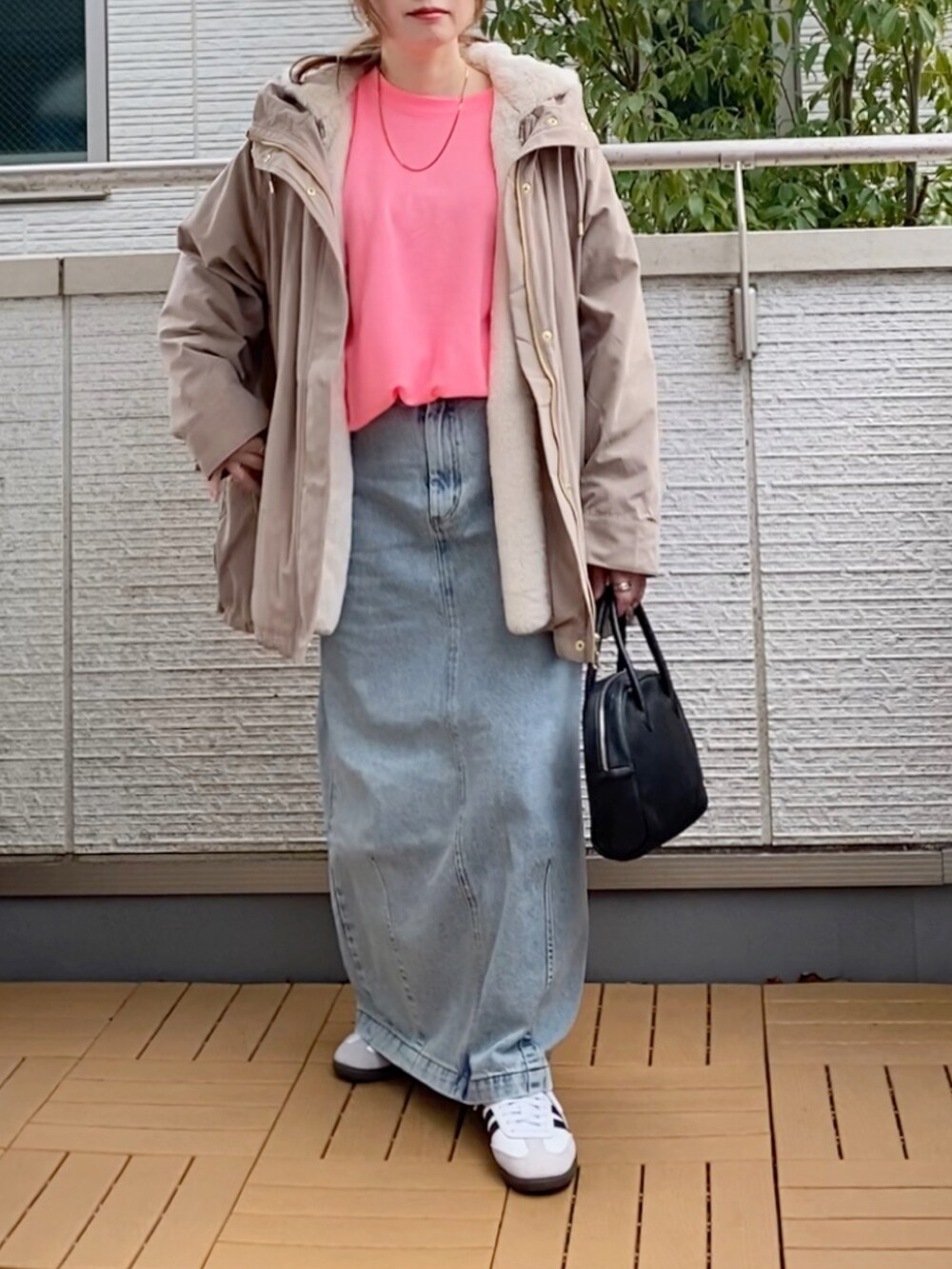 ピンク系のTシャツ/カットソー、ベージュ系のマウンテンパーカー、ブルー系のデニムスカートを着用したレディースの冬コーディネートの2枚目の写真