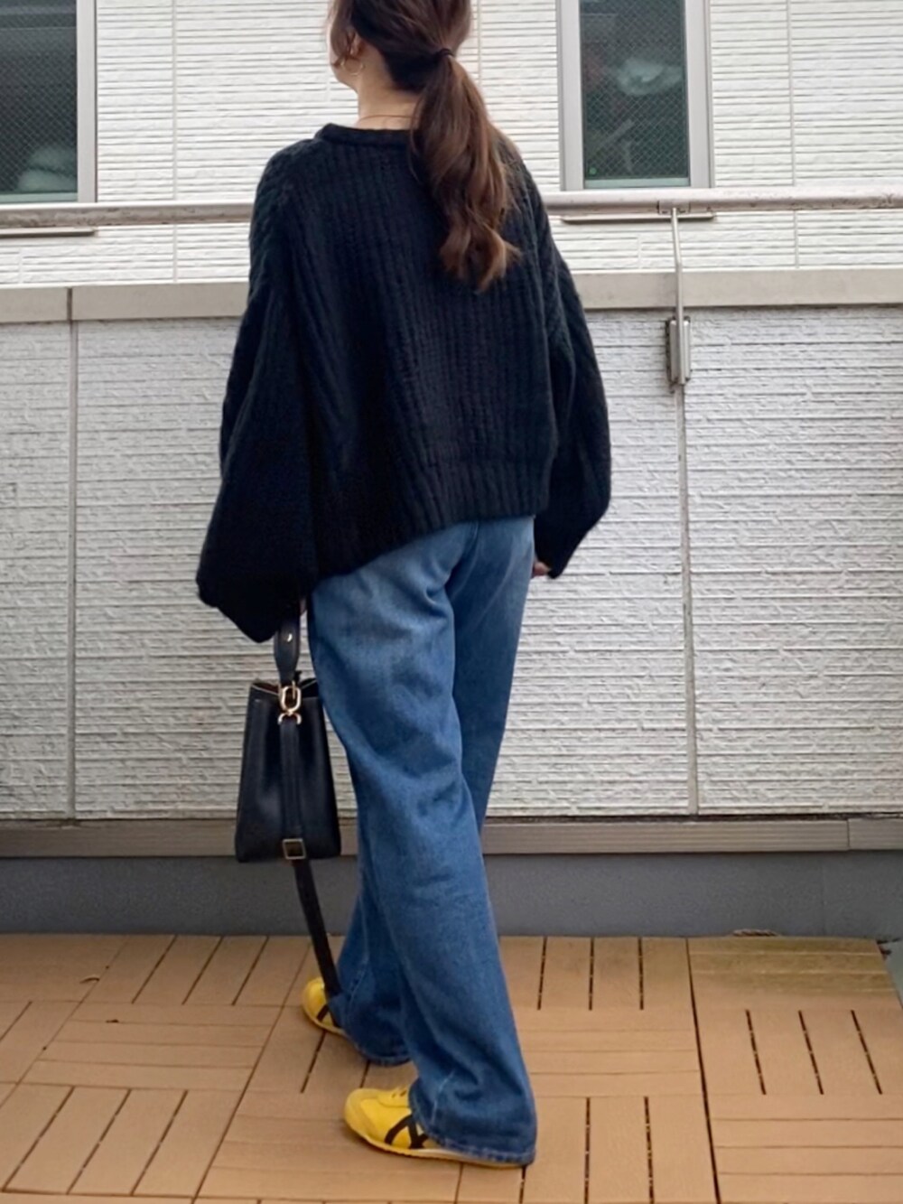 ブラック系のカーディガン/ボレロ、ブルー系のデニムパンツ、ブラック系のショルダーバッグを着用したレディースの秋コーディネートの4枚目の写真