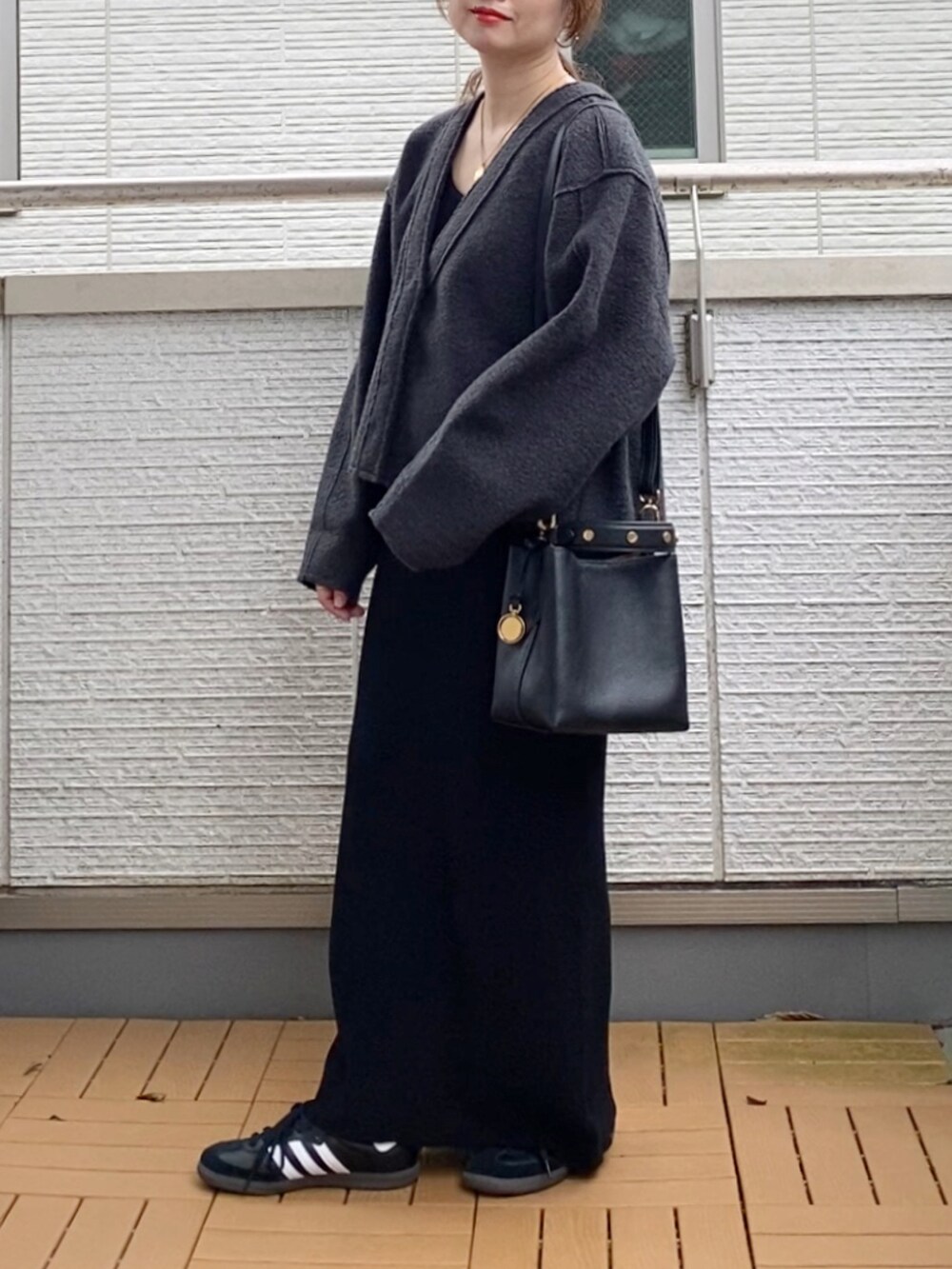 グレー系のカーディガン/ボレロ、ブラック系のワンピース、ブラック系のショルダーバッグを着用したレディースの秋コーディネートの2枚目の写真