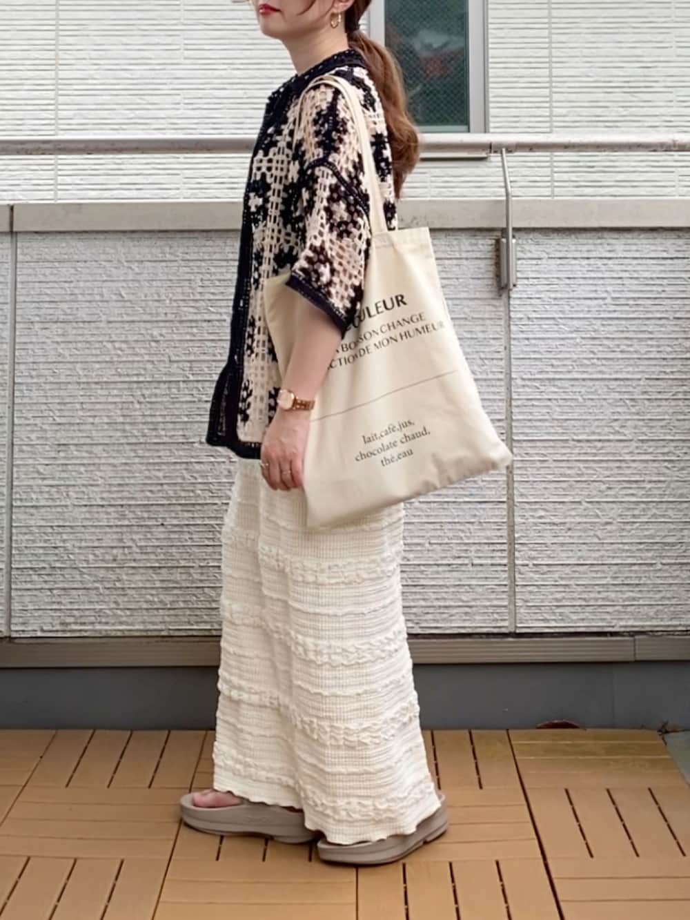 ブラック系のカーディガン/ボレロ、ホワイト系のスカート、ホワイト系のトートバッグを着用したレディースの夏コーディネートの3枚目の写真