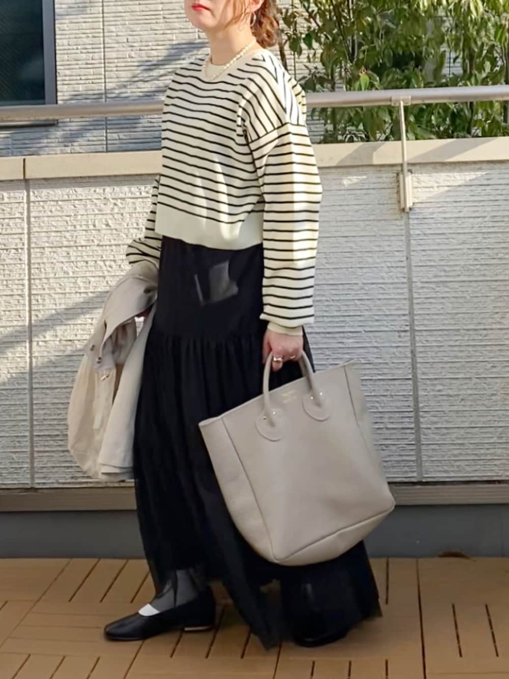 ホワイト系のマウンテンパーカー、ブラック系のカーディガン/ボレロ、ブラック系のスカートを着用したレディースの春コーディネートの4枚目の写真