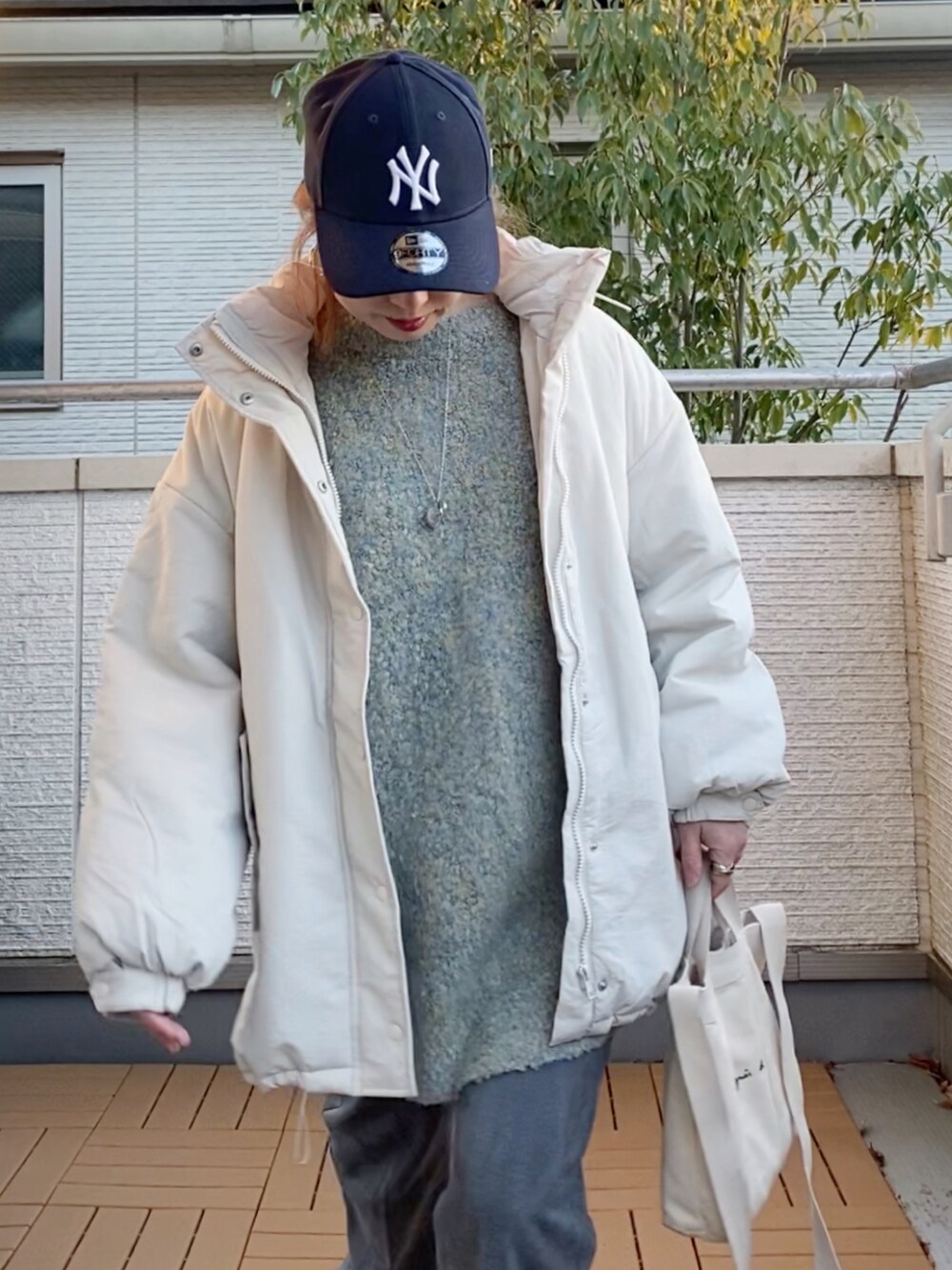 ホワイト系のダウンジャケット/コート、グレー系のカーディガン/ボレロ、グレー系のスラックスを着用したレディースの冬コーディネートの3枚目の写真