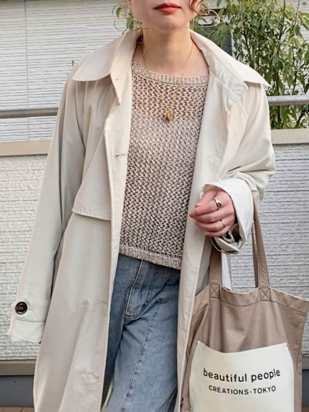 ホワイト系のトレンチコート、ベージュ系のニット/セーター、ブルー系のデニムパンツを着用したレディースの春コーディネートの2枚目の写真