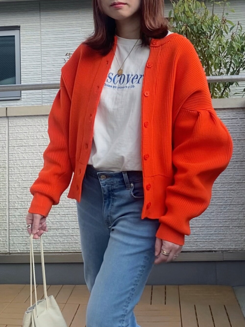 オレンジ系のカーディガン/ボレロ、ホワイト系のTシャツ/カットソー、ブルー系のデニムパンツを着用したレディースの春コーディネートの3枚目の写真
