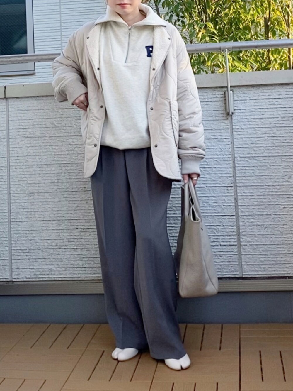 ベージュ系のブルゾン、ベージュ系のスウェット、グレー系のスラックスを着用したレディースの秋コーディネートの2枚目の写真
