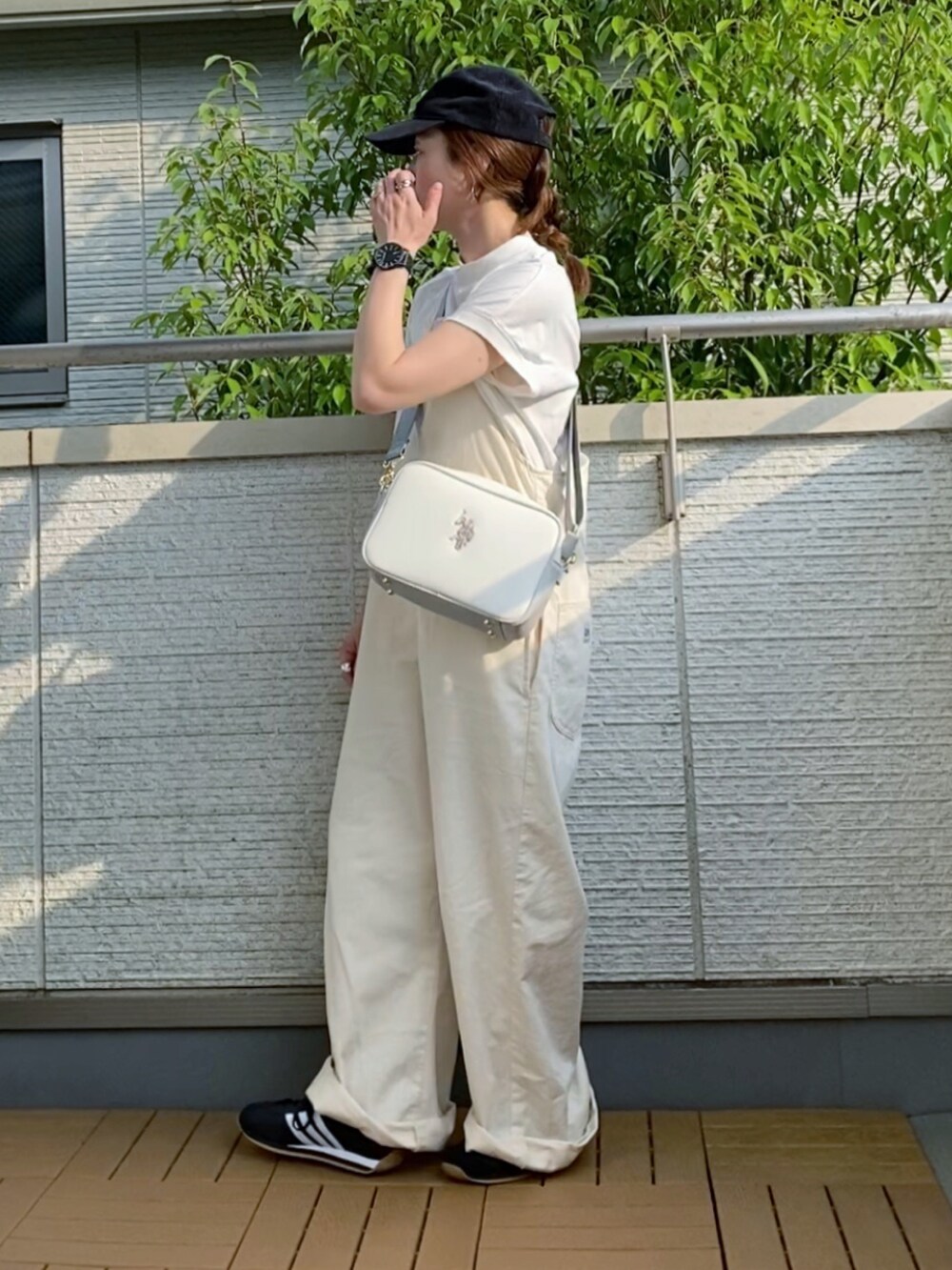 ホワイト系のサロペット/オーバーオール、ホワイト系のショルダーバッグ、ブラック系のスニーカーを着用したレディースの夏コーディネートの2枚目の写真