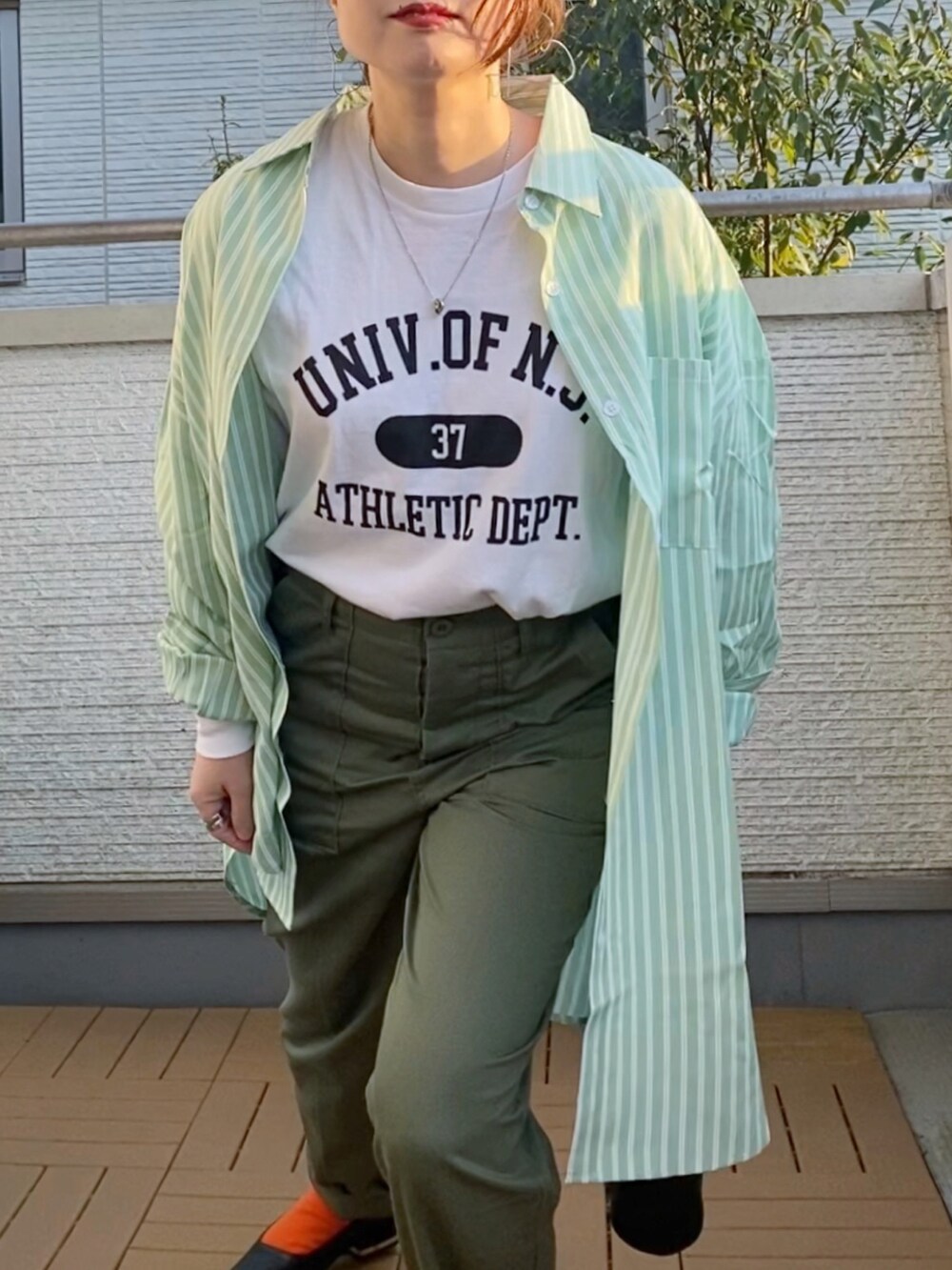 ホワイト系のTシャツ/カットソー、グリーン系のシャツ/ブラウス、グリーン系のチノパンツを着用したレディースの冬コーディネートの2枚目の写真