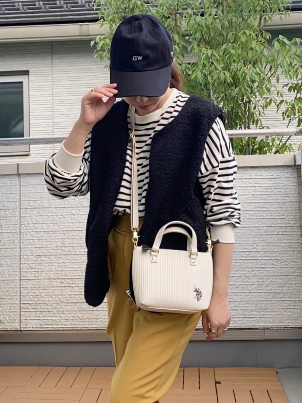 ホワイト系のショルダーバッグ、ブラック系のベスト、ブラック系のTシャツ/カットソーを着用したレディースの秋コーディネートの3枚目の写真