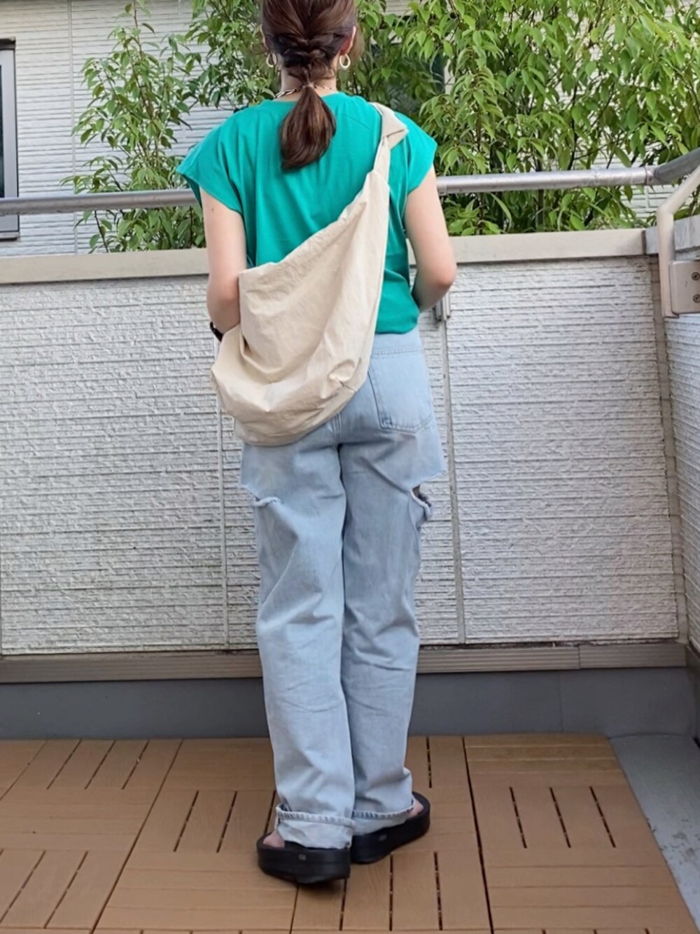 グリーン系のTシャツ/カットソー、ブルー系のデニムパンツ、ホワイト系のショルダーバッグを着用したレディースの夏コーディネートの3枚目の写真