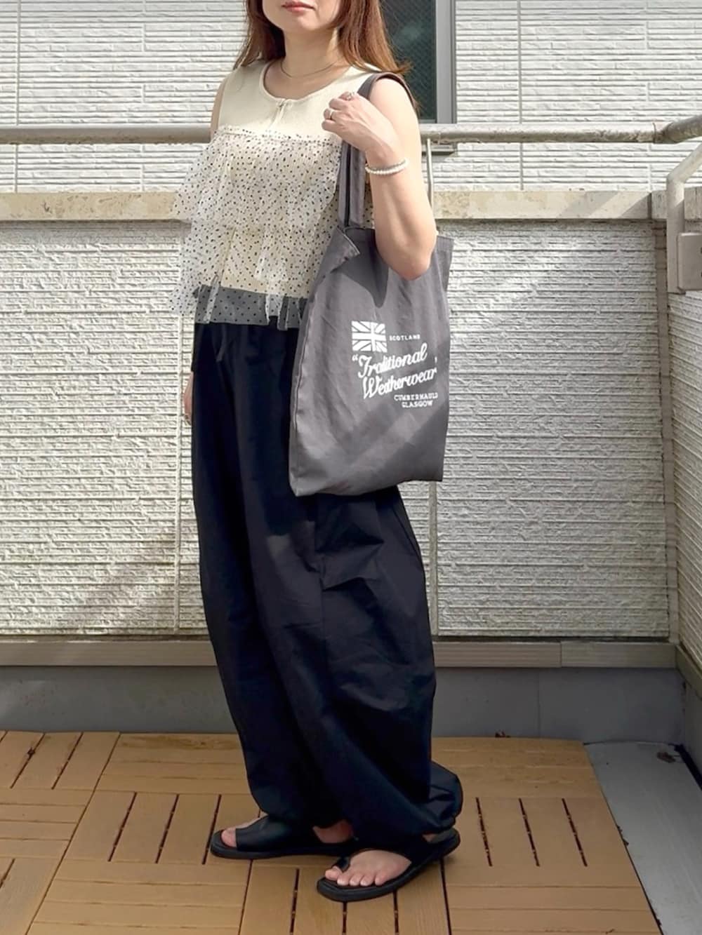 ホワイト系のニット/セーター、ブラック系のその他パンツを着用したレディースの夏コーディネートの2枚目の写真