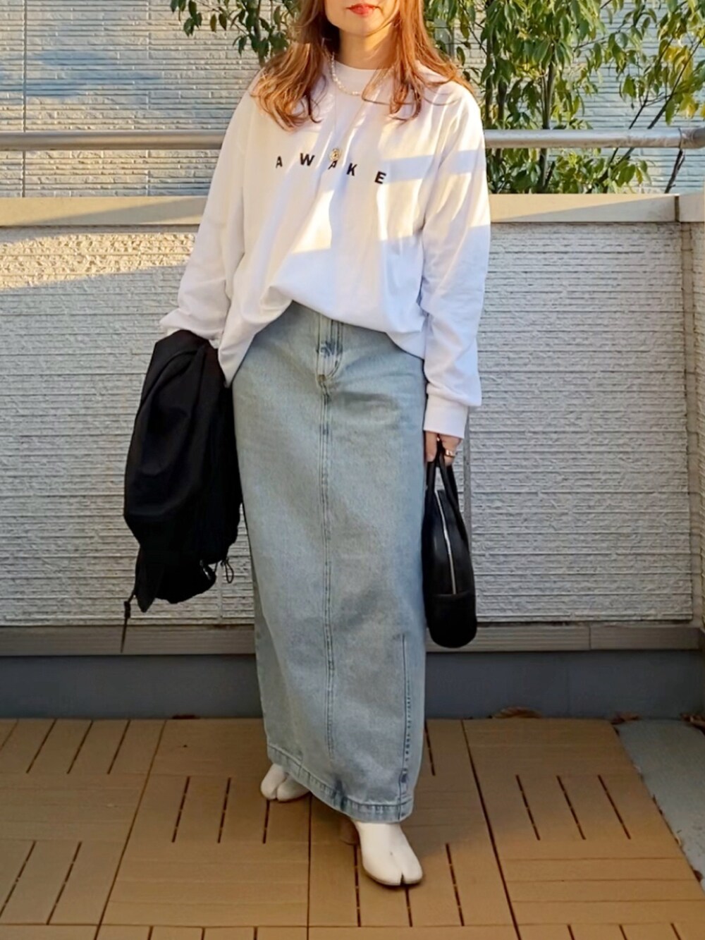 ホワイト系のTシャツ/カットソー、ブラック系のその他アウター、ブルー系のデニムスカートを着用したレディースの春コーディネートの3枚目の写真