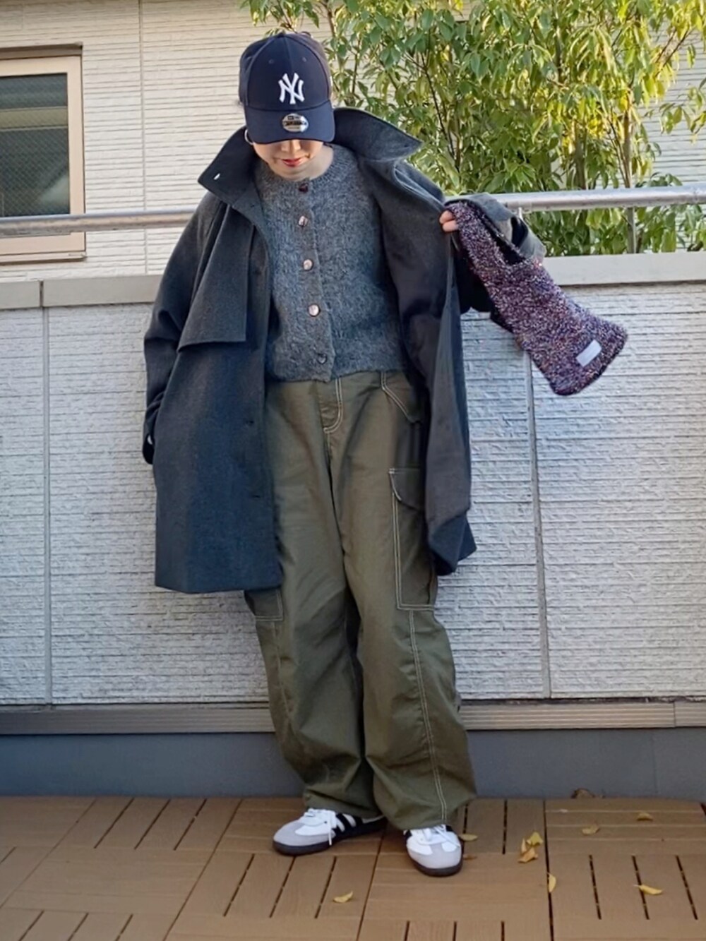 グレー系のトレンチコート、グレー系のカーディガン/ボレロ、グリーン系のカーゴパンツを着用したレディースの秋コーディネートの2枚目の写真