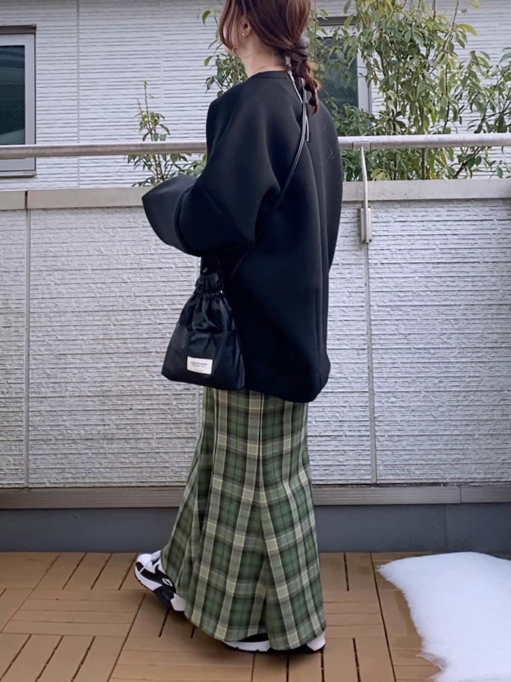 ブラック系のスウェット、グリーン系のスカート、ブラック系のショルダーバッグを着用したレディースの冬コーディネートの2枚目の写真