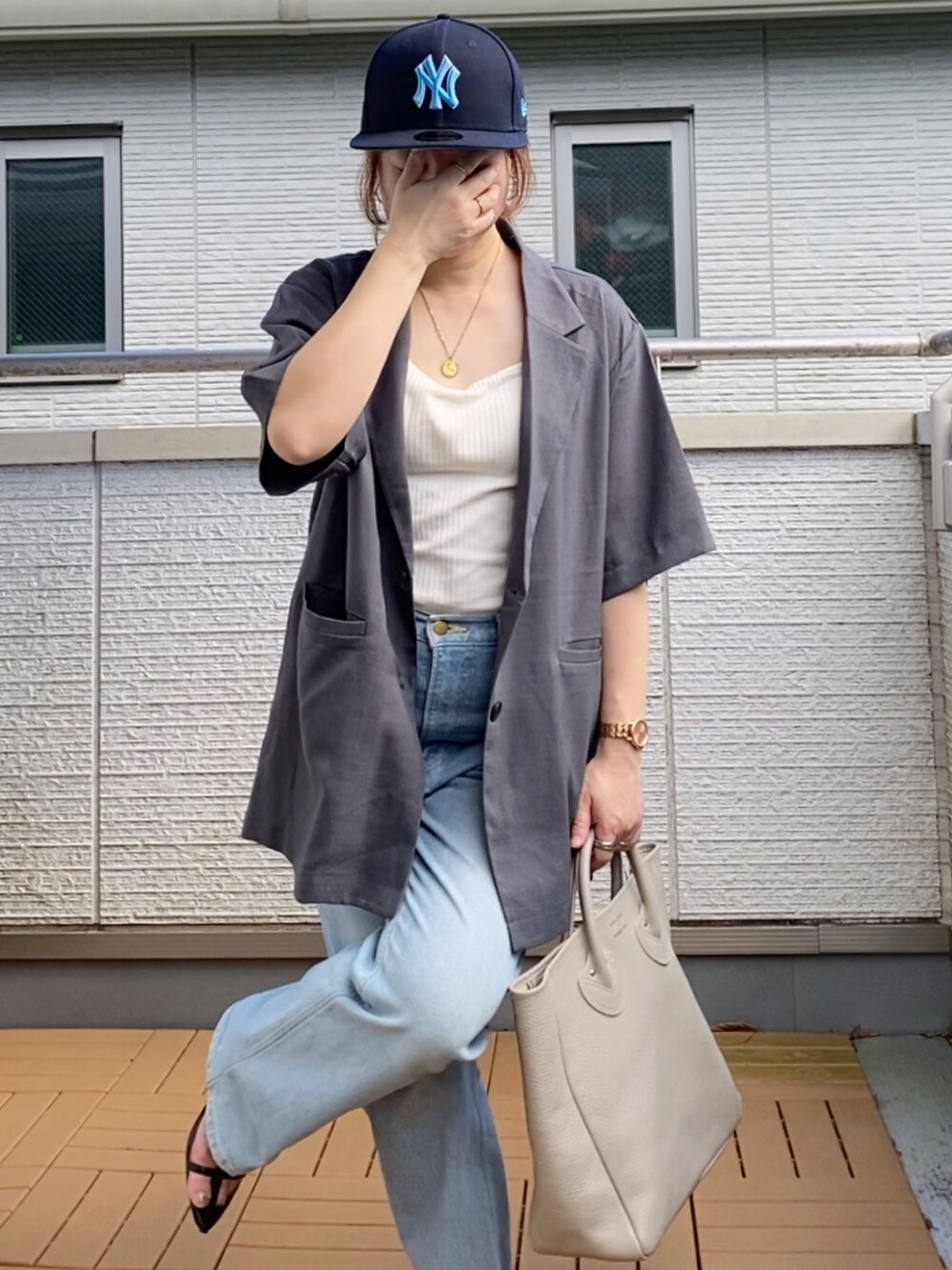 グレー系のテーラードジャケット、ホワイト系のタンクトップ、ブルー系のデニムパンツを着用したレディースの夏コーディネートの4枚目の写真