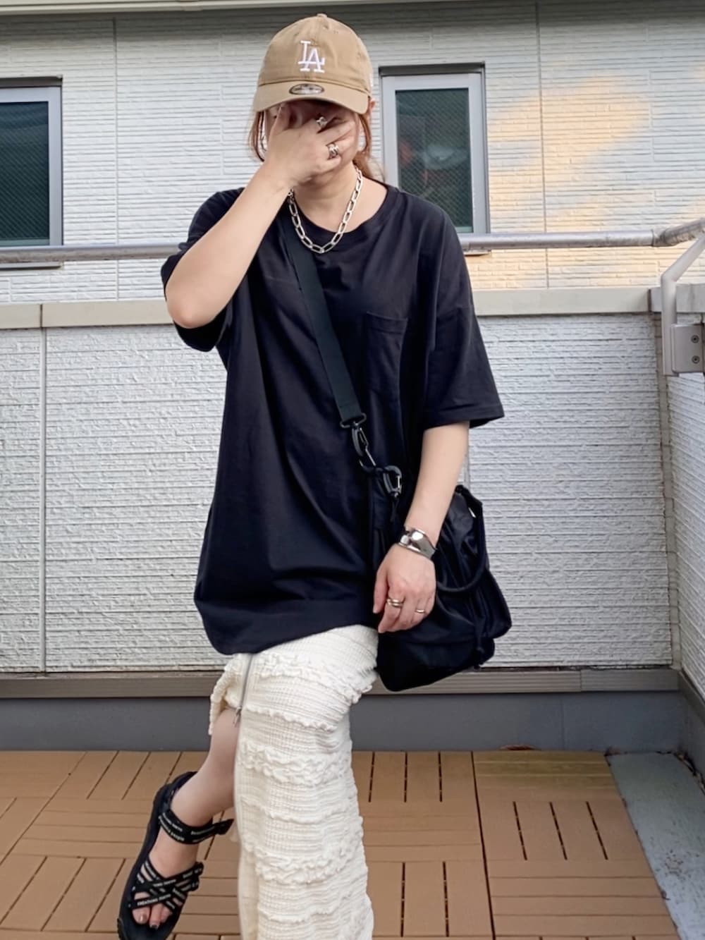 ブラック系のTシャツ/カットソー、ホワイト系のスカート、ブラック系のショルダーバッグを着用したレディースの夏コーディネートの3枚目の写真