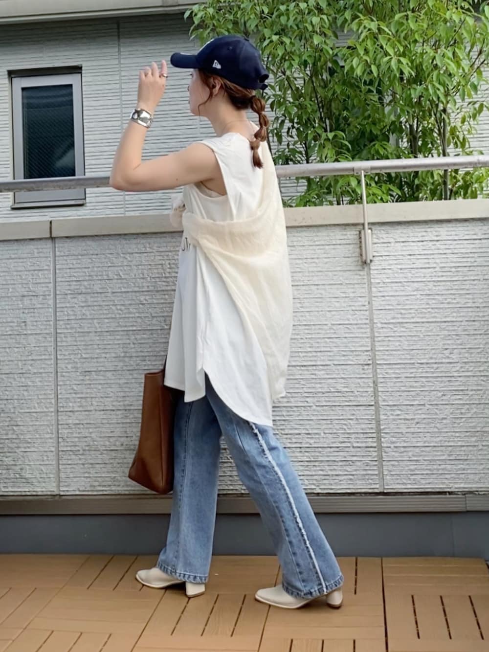 ホワイト系のタンクトップ、ブルー系のデニムパンツ、ブラウン系のトートバッグを着用したレディースの夏コーディネートの4枚目の写真
