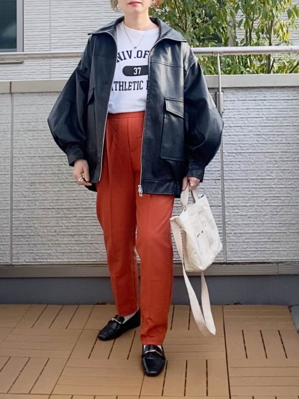 ブラック系のライダースジャケット、ホワイト系のTシャツ/カットソー、オレンジ系のその他パンツを着用したレディースの冬コーディネートの5枚目の写真