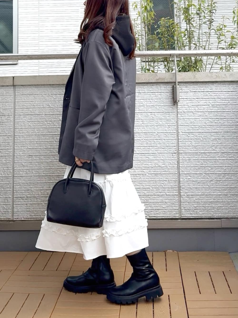 グレー系のテーラードジャケット、ホワイト系のスカート、ブラック系のブーツを着用したレディースの春コーディネートの3枚目の写真