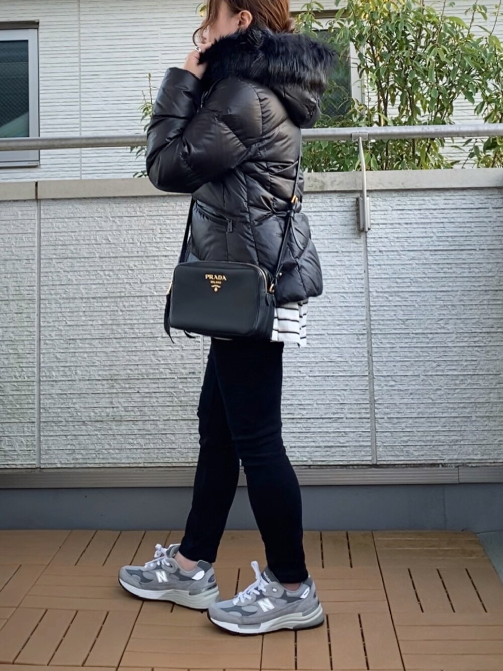 ブラック系のダウンジャケット/コート、ホワイト系のTシャツ/カットソー、グレー系のスニーカーを着用したレディースの秋コーディネートの2枚目の写真