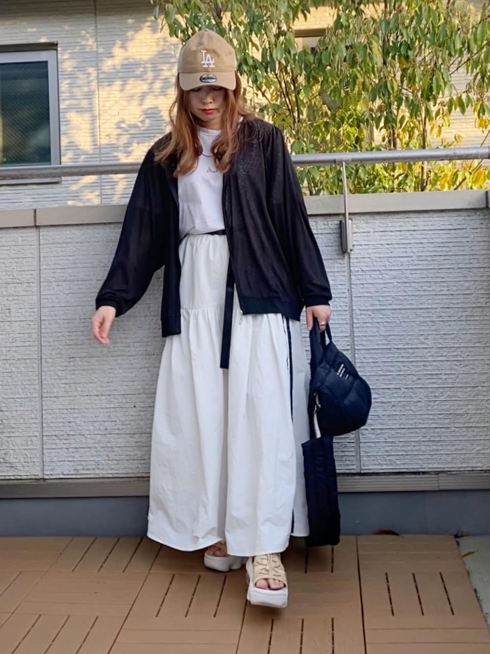 ブラック系のブルゾン、イエロー系のTシャツ/カットソー、ホワイト系のスカートを着用したレディースの春コーディネートの2枚目の写真