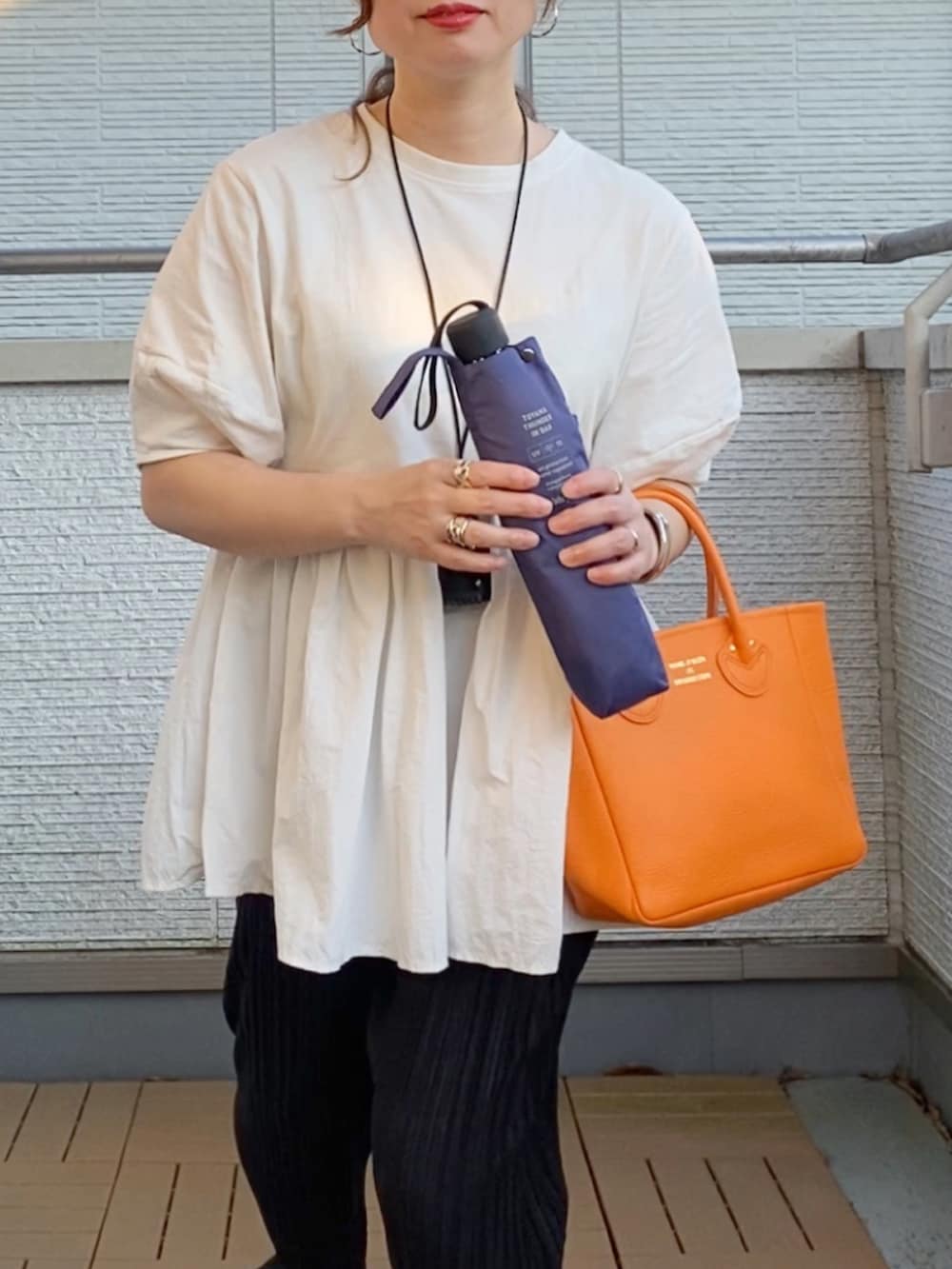 ホワイト系のTシャツ/カットソー、ブラック系のその他パンツ、オレンジ系のトートバッグを着用したレディースの夏コーディネートの4枚目の写真