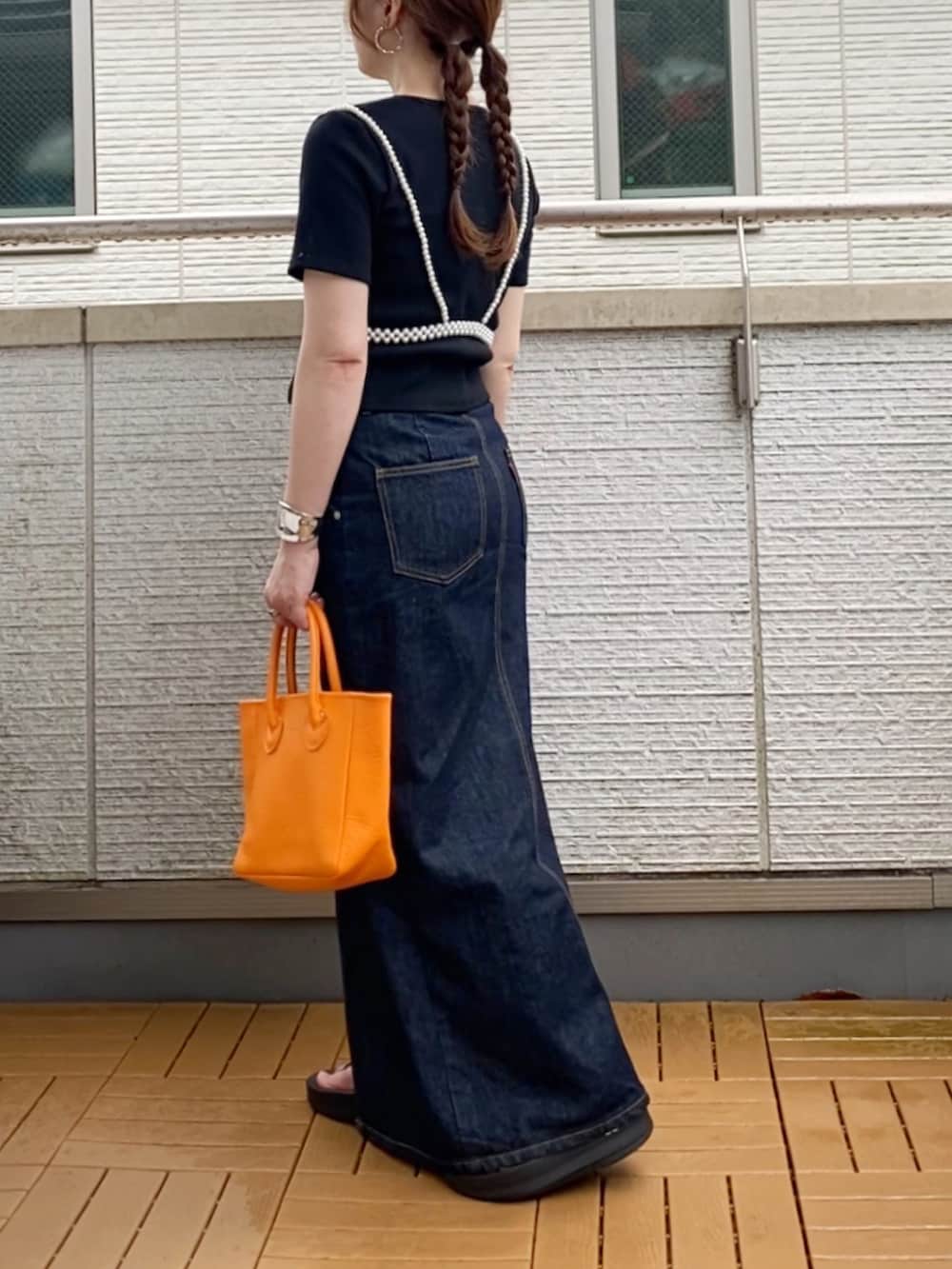 ブラック系のTシャツ/カットソー、ブルー系のデニムスカート、オレンジ系のトートバッグを着用したレディースの夏コーディネートの2枚目の写真