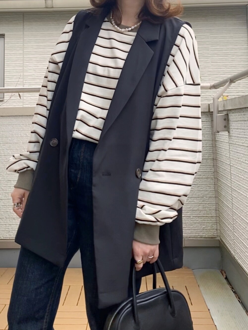 ホワイト系のTシャツ/カットソー、ブラック系のベスト、ブルー系のデニムパンツを着用したレディースの春コーディネートの2枚目の写真