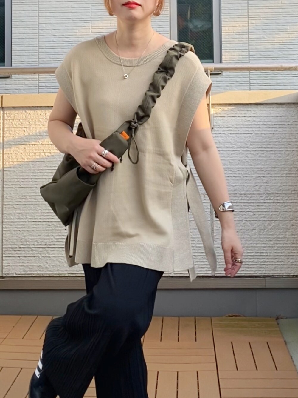 ベージュ系のニット/セーター、ブラック系のその他パンツ、グリーン系のショルダーバッグを着用したレディースの秋コーディネートの5枚目の写真