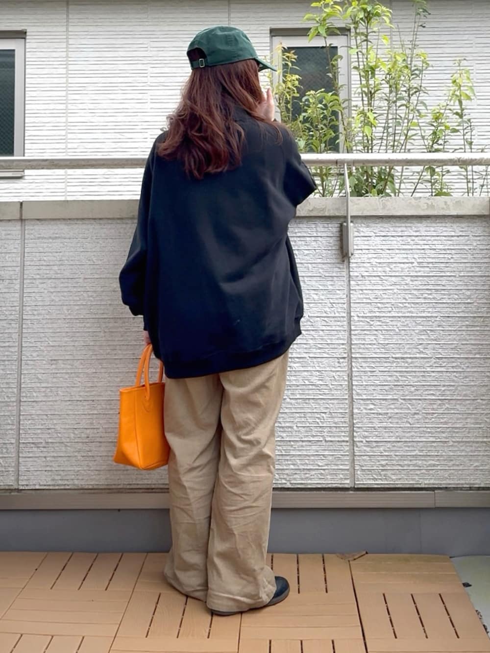 ブラック系のスウェット、オレンジ系のトートバッグ、ブラック系のスニーカーを着用したレディースの秋コーディネートの4枚目の写真