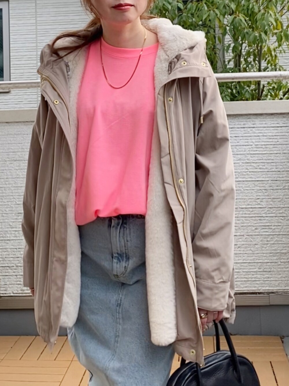 ピンク系のTシャツ/カットソー、ベージュ系のマウンテンパーカー、ブルー系のデニムスカートを着用したレディースの冬コーディネートの3枚目の写真