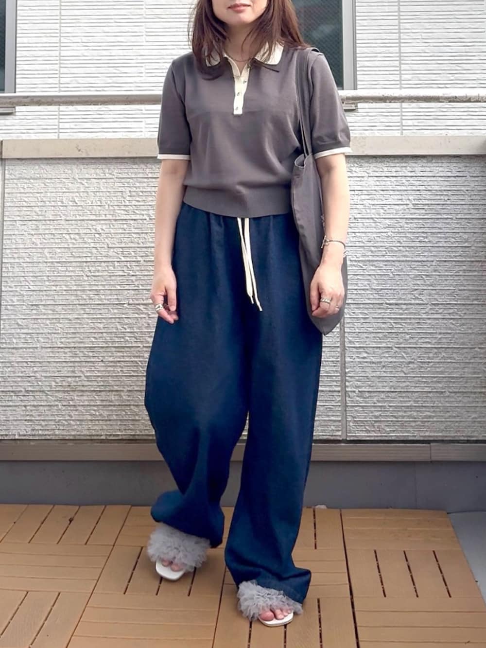 グレー系のポロシャツ、グレー系のサンダル、ブルー系のデニムパンツを着用したレディースの夏コーディネートの2枚目の写真