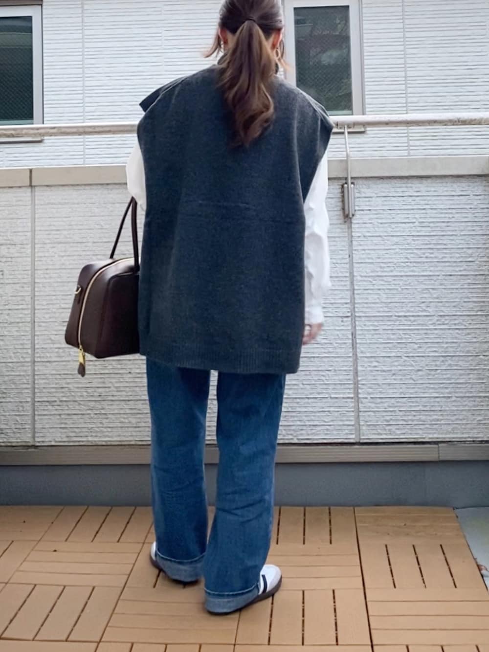 グレー系のベスト、ホワイト系のシャツ/ブラウス、ブルー系のデニムパンツを着用したレディースの冬コーディネートの4枚目の写真