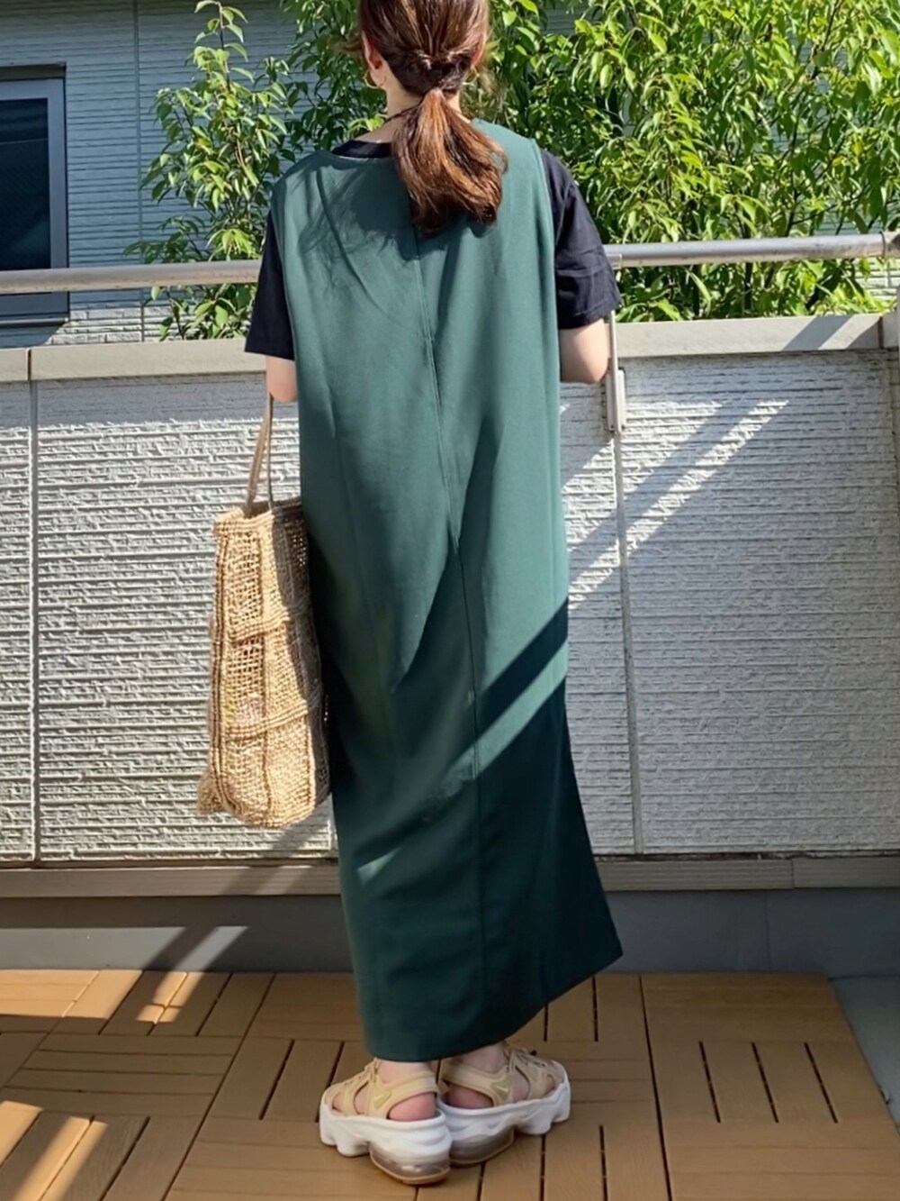 グリーン系のワンピース、ブラック系のTシャツ/カットソー、ベージュ系のバッグを着用したレディースの夏コーディネートの2枚目の写真