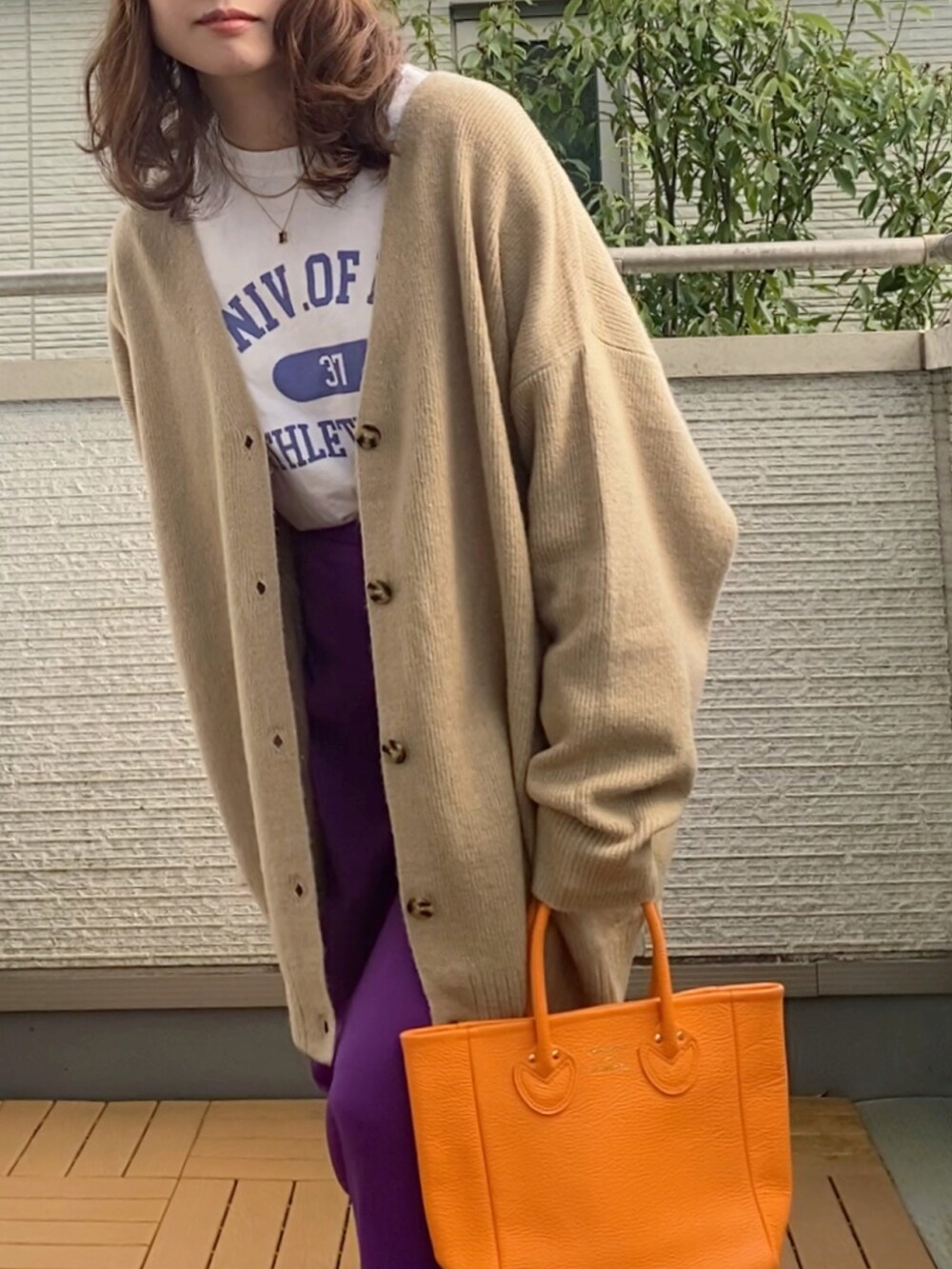 ベージュ系のカーディガン/ボレロ、ホワイト系のTシャツ/カットソー、パープル系のスカートを着用したレディースの秋コーディネートの2枚目の写真