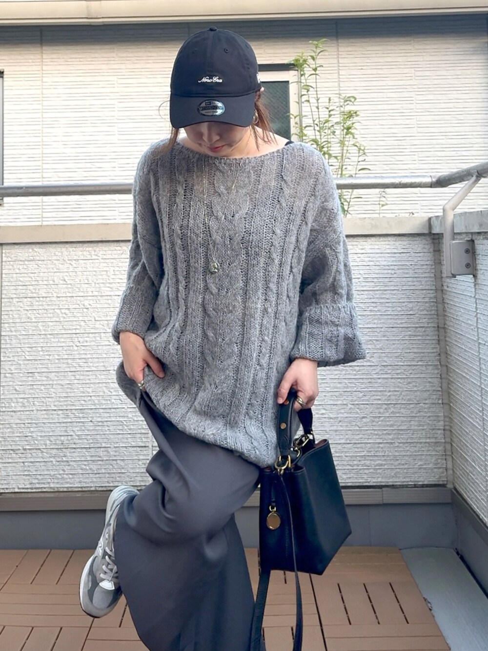 グレー系のニット/セーター、ブラック系のショルダーバッグ、グレー系のスカートを着用したレディースの夏コーディネートの5枚目の写真