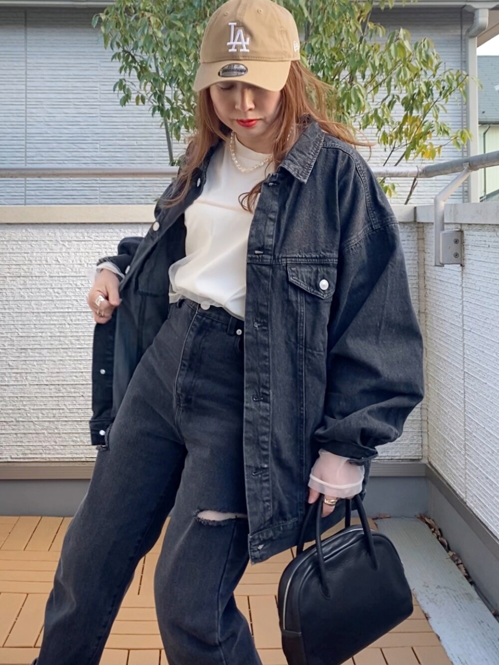 ブラック系のデニムジャケット、ホワイト系のTシャツ/カットソー、ブラック系のデニムパンツを着用したレディースの春コーディネートの4枚目の写真