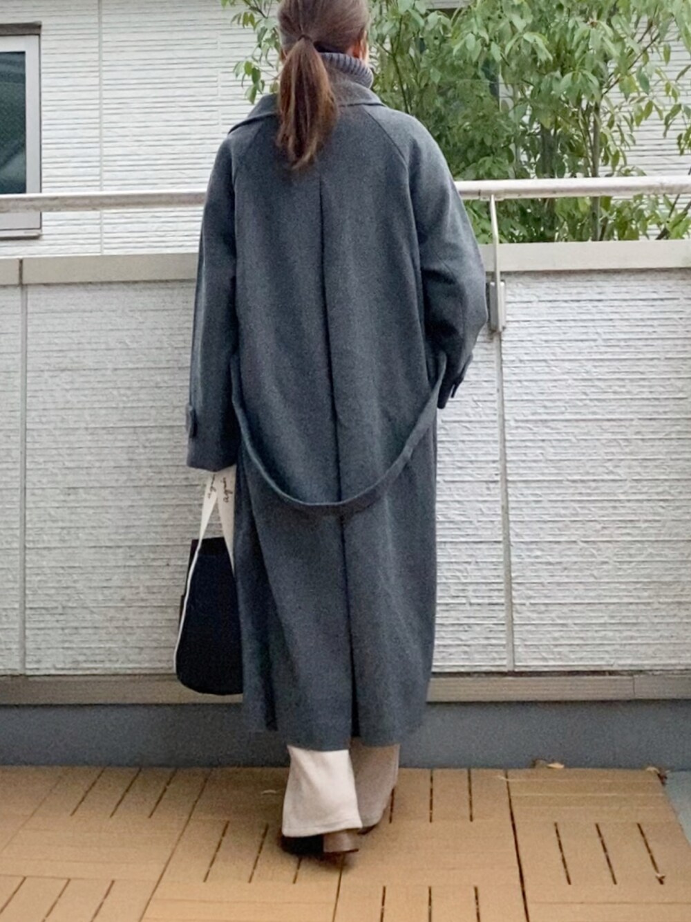 グレー系のステンカラーコート、グレー系のニット/セーター、ベージュ系のその他パンツを着用したレディースの冬コーディネートの3枚目の写真