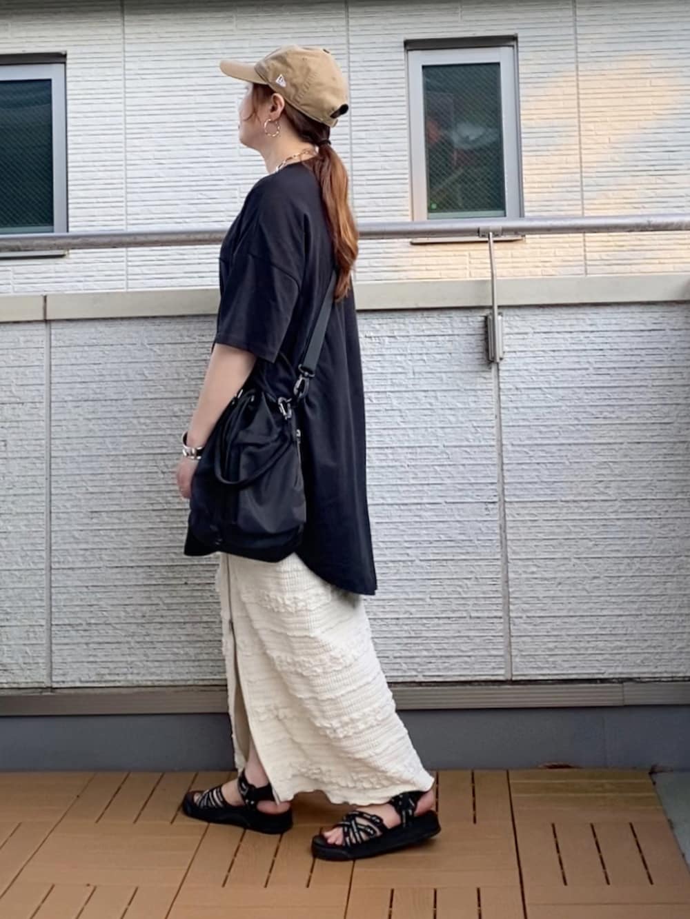 ブラック系のTシャツ/カットソー、ホワイト系のスカート、ブラック系のショルダーバッグを着用したレディースの夏コーディネートの2枚目の写真