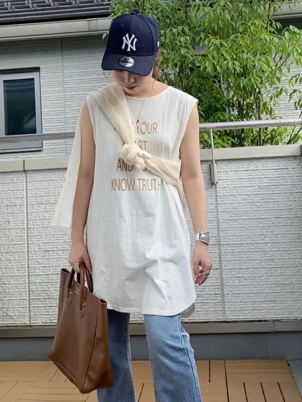 ホワイト系のタンクトップ、ブルー系のデニムパンツ、ブラウン系のトートバッグを着用したレディースの夏コーディネートの3枚目の写真