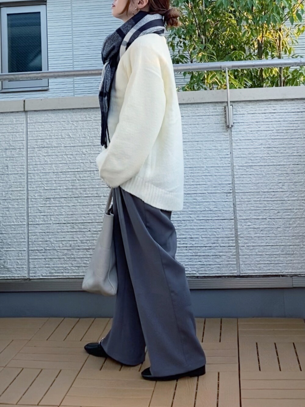 ホワイト系のニット/セーター、グレー系のスラックス、ベージュ系のトートバッグを着用したレディースの秋コーディネートの2枚目の写真