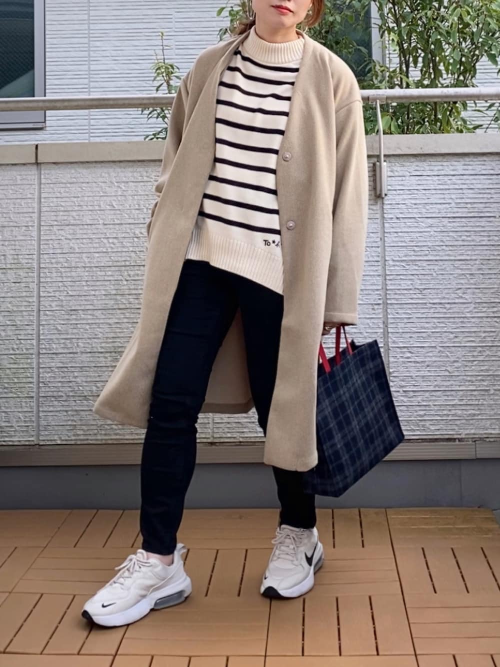 ベージュ系のその他アウター、ホワイト系のニット/セーター、ブルー系のトートバッグを着用したレディースの秋コーディネートの2枚目の写真