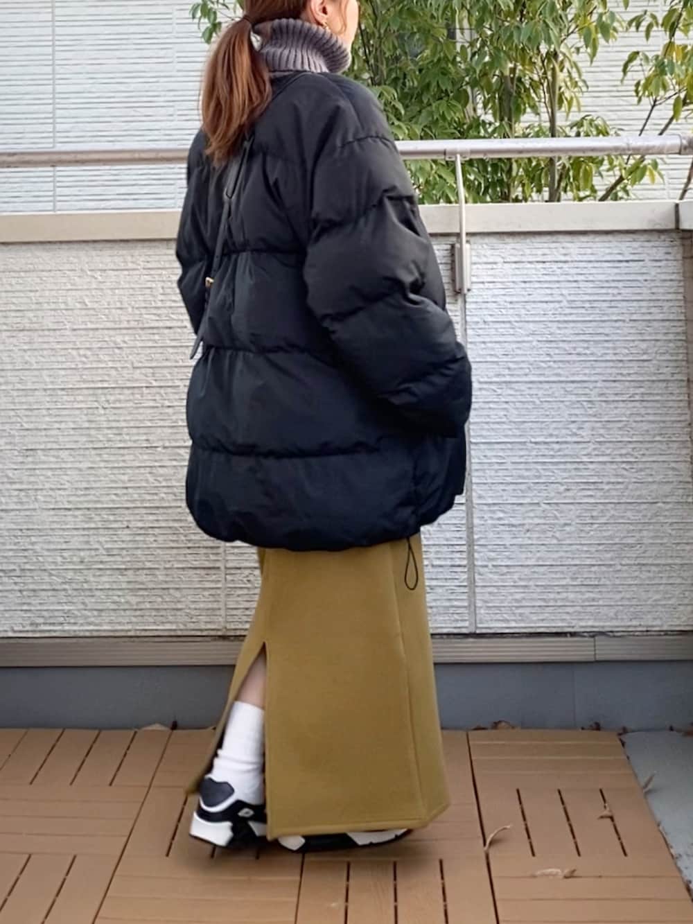 ブラック系のダウンジャケット/コート、グレー系のニット/セーター、グリーン系のスカートを着用したレディースの冬コーディネートの3枚目の写真