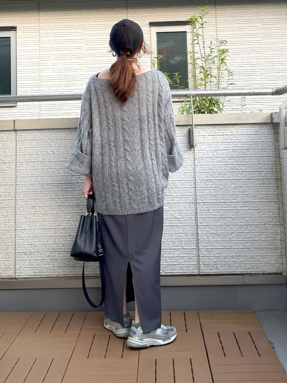 グレー系のニット/セーター、ブラック系のショルダーバッグ、グレー系のスカートを着用したレディースの夏コーディネートの4枚目の写真