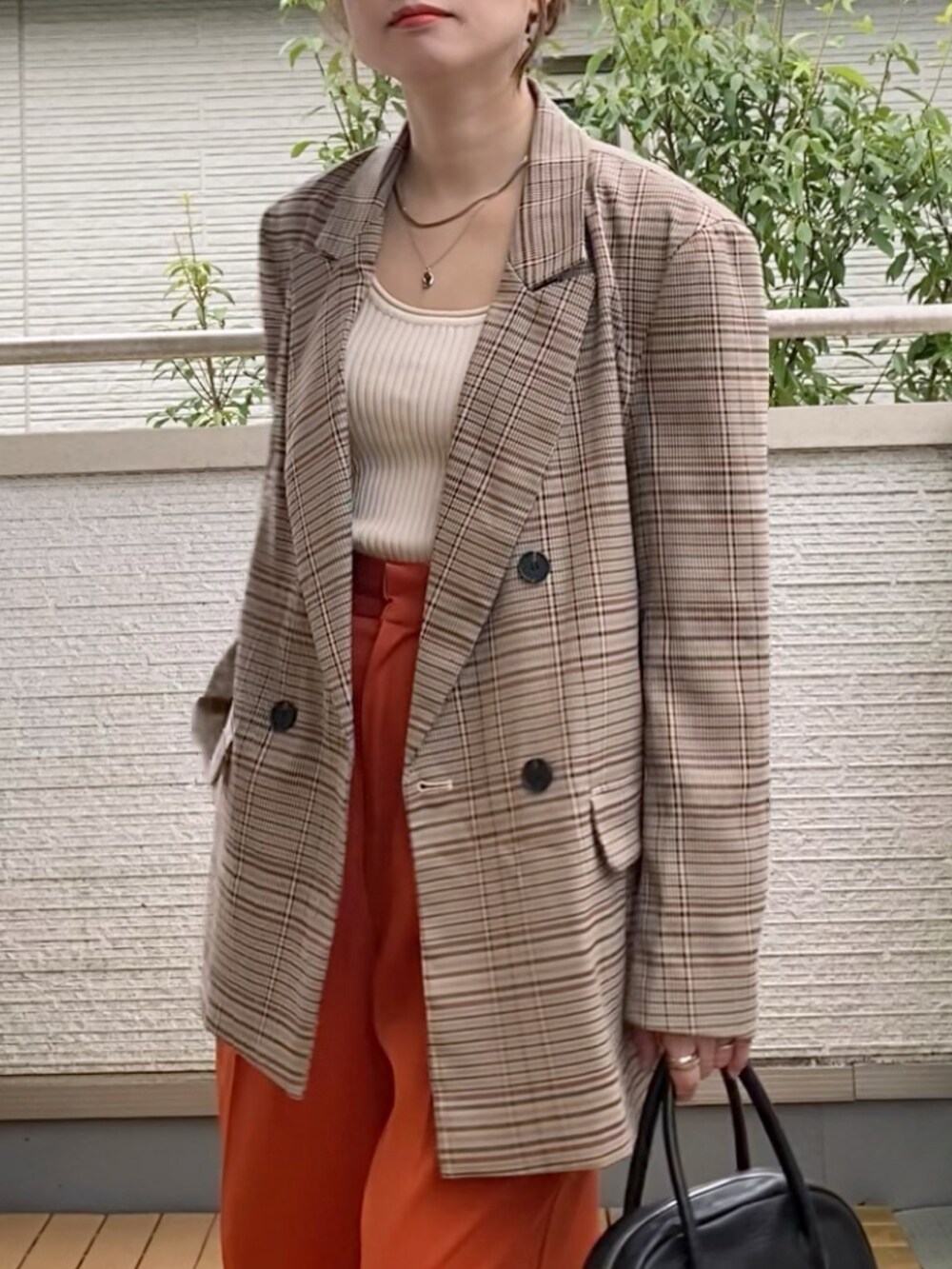 ブラウン系のテーラードジャケット、オレンジ系のスラックス、ブラック系のショルダーバッグを着用したレディースの秋コーディネートの3枚目の写真