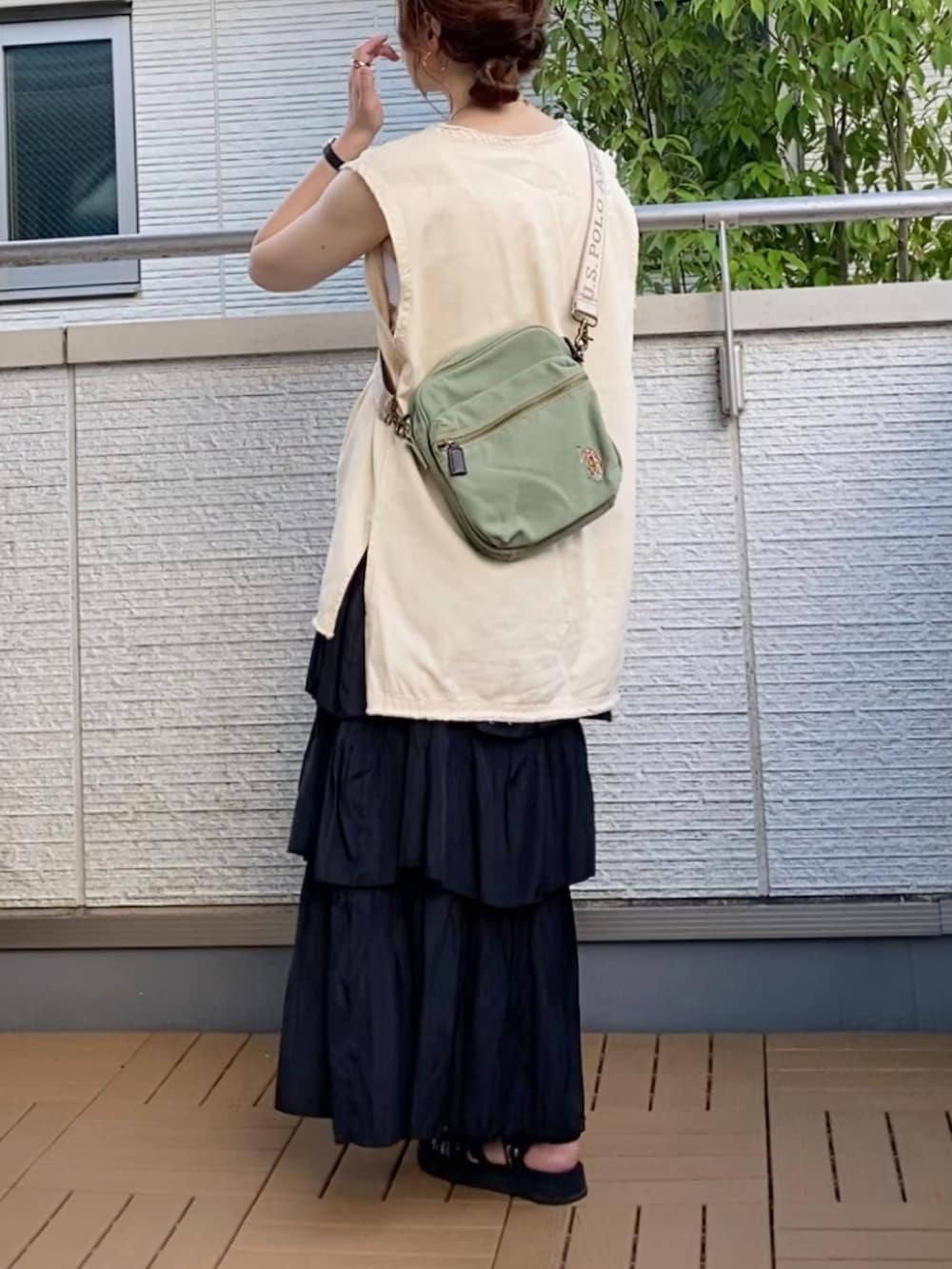 ホワイト系のベスト、ブラック系のスカート、グリーン系のショルダーバッグを着用したレディースの夏コーディネートの2枚目の写真