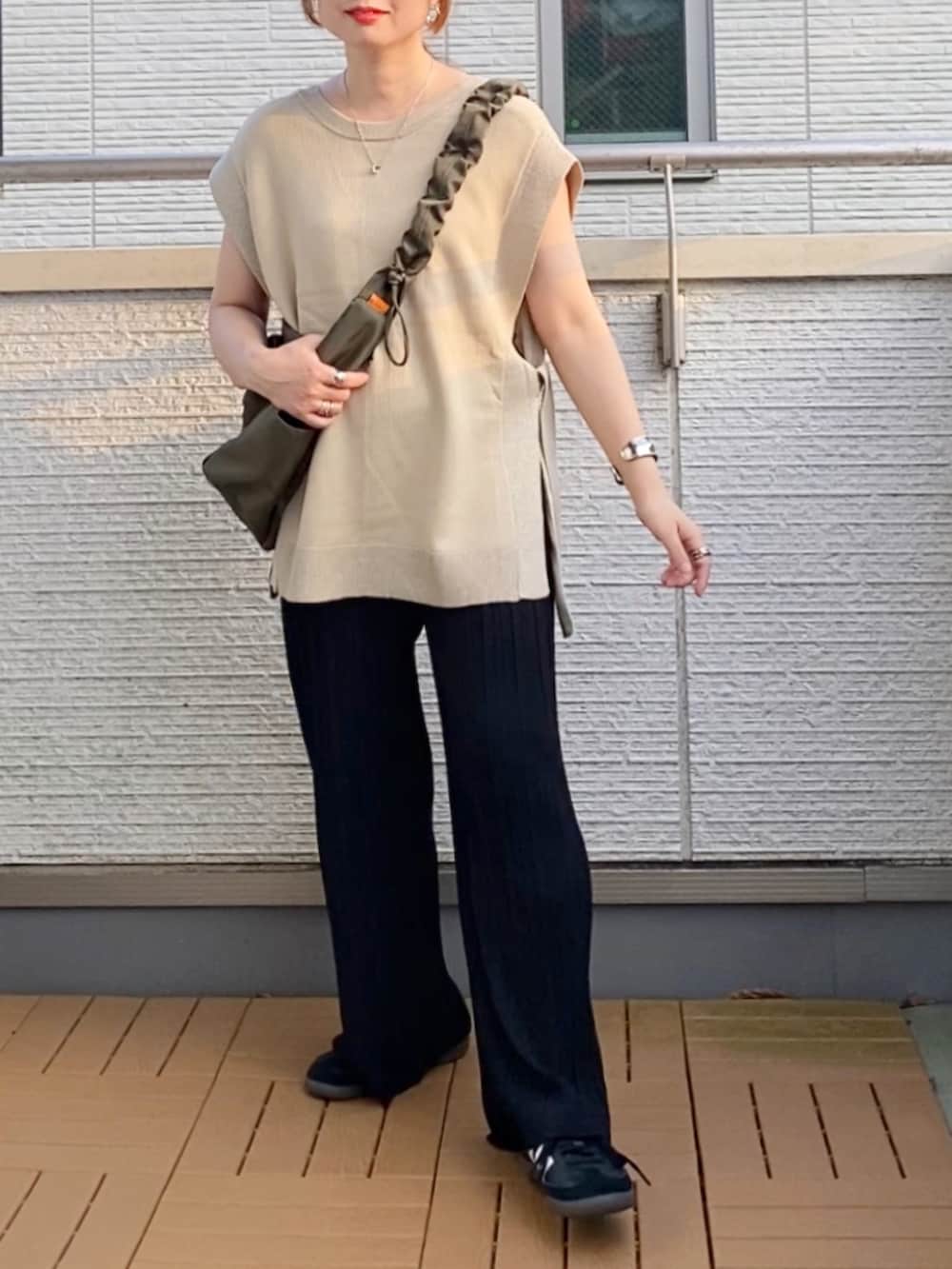 ベージュ系のニット/セーター、ブラック系のその他パンツ、グリーン系のショルダーバッグを着用したレディースの秋コーディネートの2枚目の写真