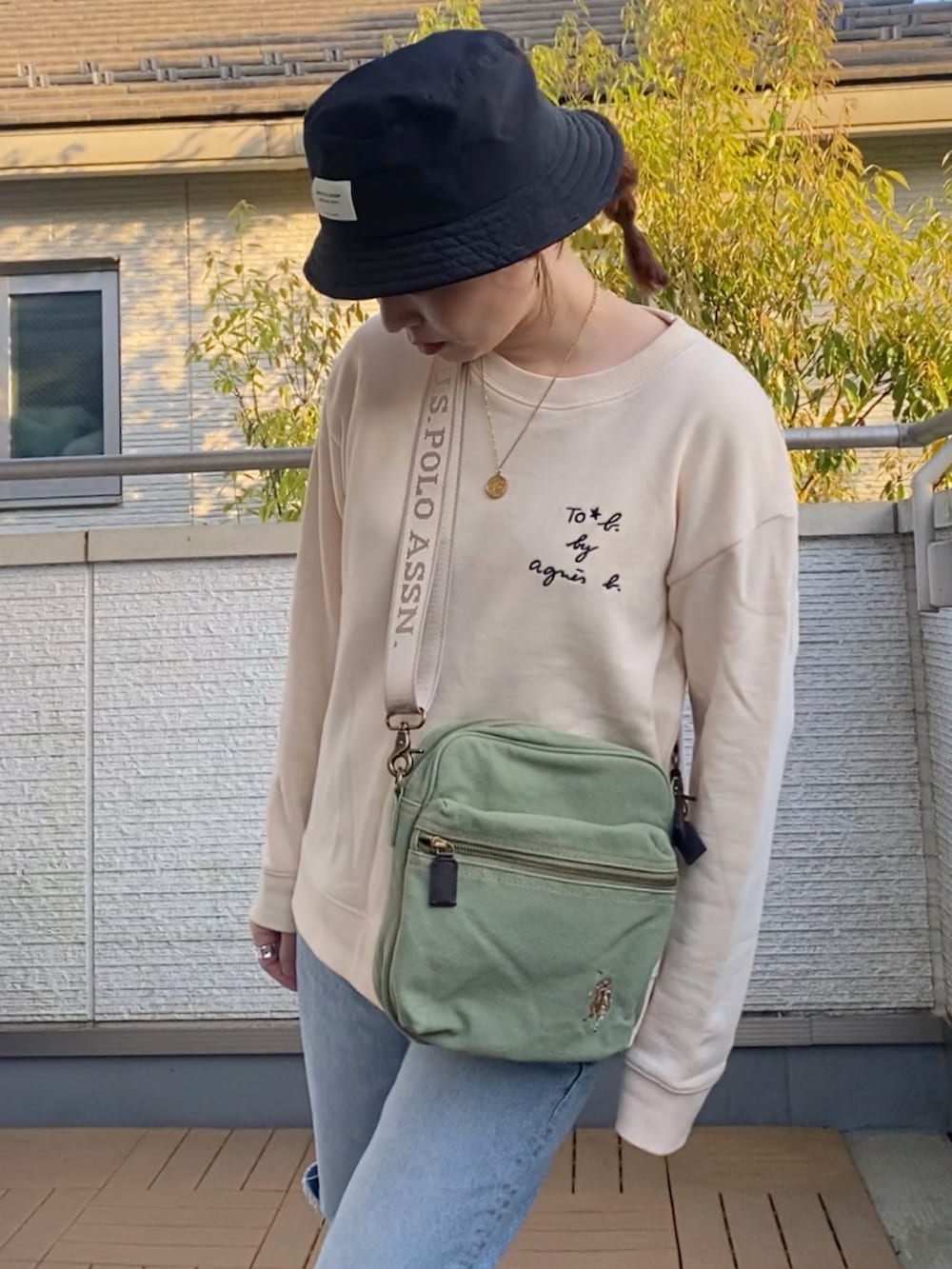 ホワイト系のスウェット、ブルー系のデニムパンツ、グリーン系のショルダーバッグを着用したレディースの春コーディネートの4枚目の写真