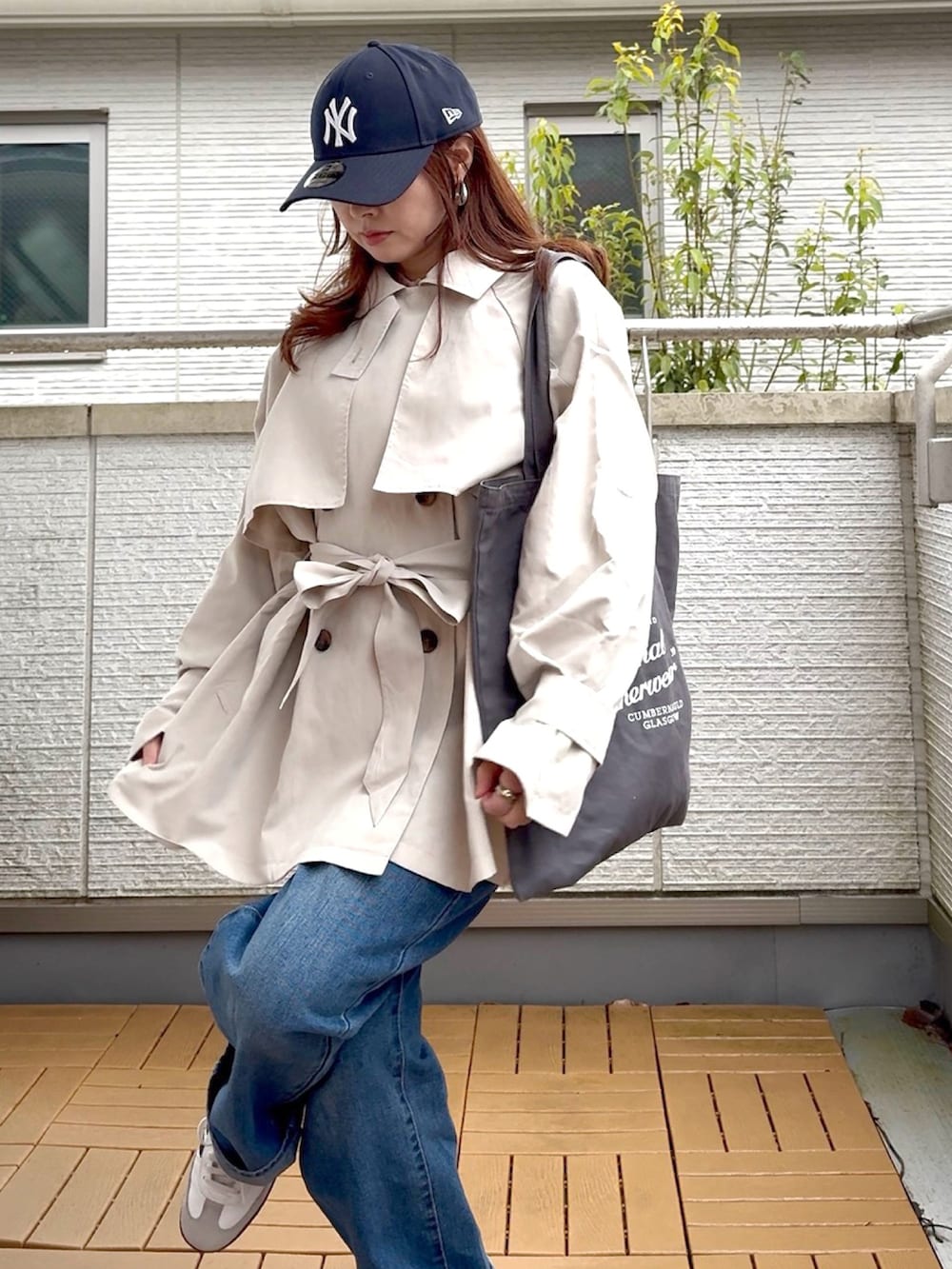 ホワイト系のトレンチコート、ブルー系のデニムパンツ、ホワイト系のスニーカーを着用したレディースの春コーディネートの4枚目の写真