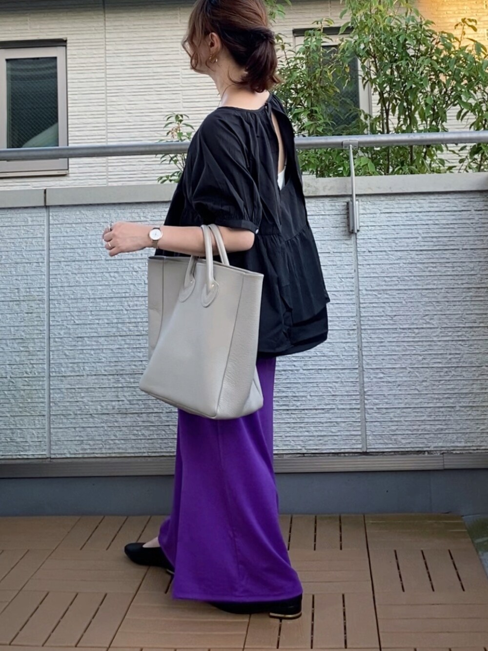 ブラック系のシャツ/ブラウス、パープル系のスカート、ベージュ系のトートバッグを着用したレディースの夏コーディネートの2枚目の写真